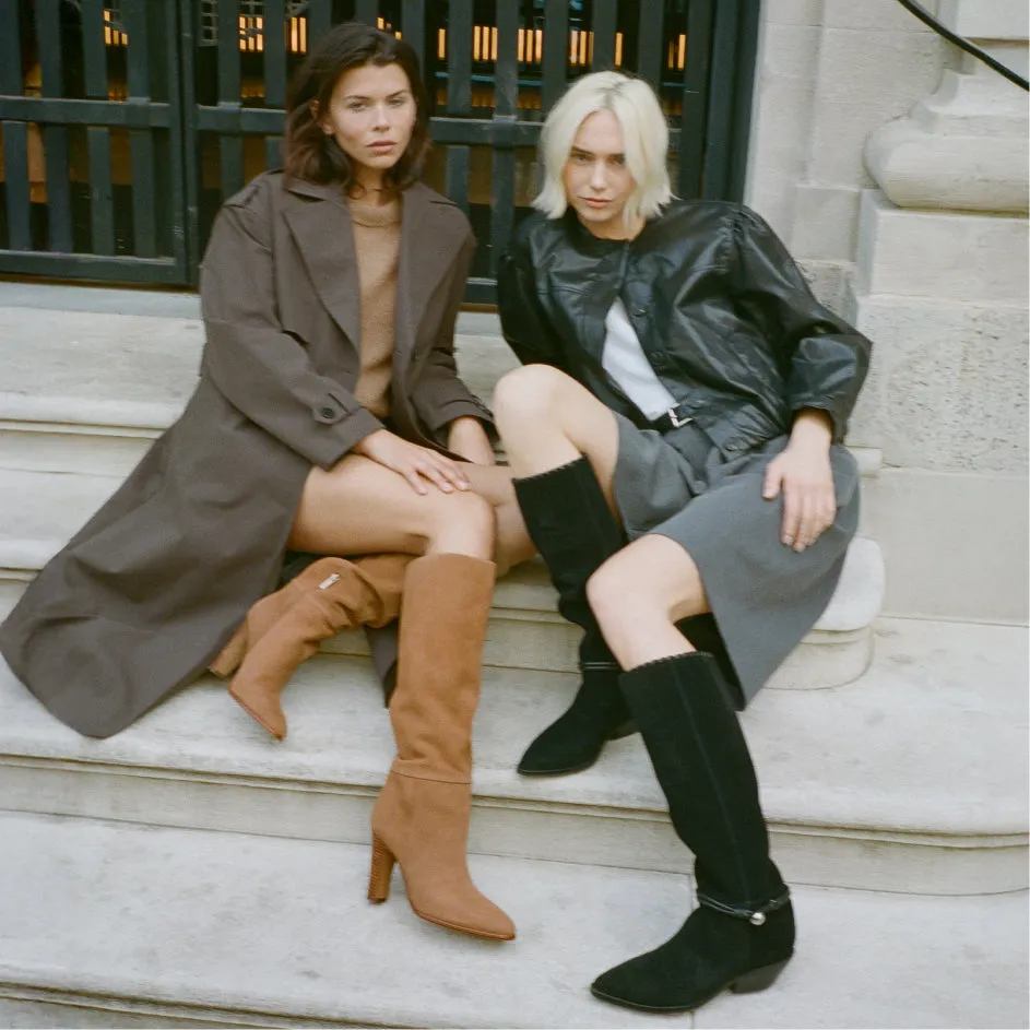 Two women seated on stone steps in knee-high boots, from the Women's Boots Collection